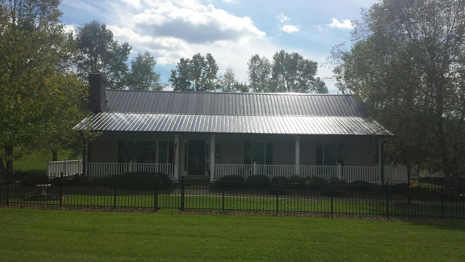 Gray metal roof on a brick ranch with a full width front porch — Gutter Guard Installation work by our crew in Ocoee
